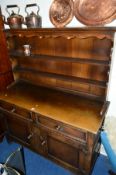 A REPRODUCTION OAK DRESSER, with a two tier plate rack above two drawers and cupboard base,