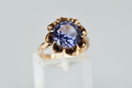 A GEM RING, the circular synthetic colour change sapphire, claw set in a floral design mount, ring