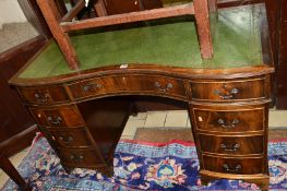 A REPRODUCTION MAHOGANY SERPENTINE PEDESTAL DESK, the green leather tooled top above a various