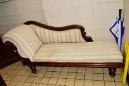 A VICTORIAN FLAME MAHOGANY CHAISE LONGUE, with a scrolled end and baluster legs on brass casters