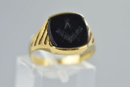 A 9CT GOLD ONYX MASONIC SIGNET RING, the central onyx panel carved with a square and compasses to