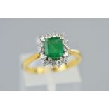 AN 18CT GOLD EMERALD AND DIAMOND CLUSTER RING, designed as a central rectangular cut emerald