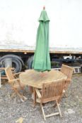 AN OCTAGONAL TEAK GARDEN TABLE, with four folding chairs and a parasol (6)