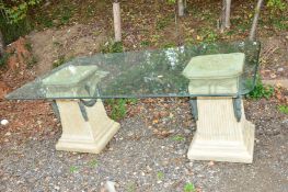 A GLASS TOPPED GARDEN TABLE, with two stone effect plastic column supports, approximately 202cm x