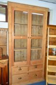 A TALL VICTORIAN PINE GLAZED TWO DOOR CABINET, above two short and one long drawer, approximate