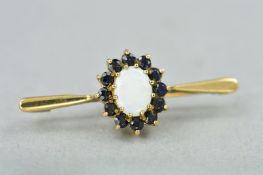 A 9CT OPAL AND SAPPHIRE BROOCH, the central opal cabochon within a sapphire surround to the