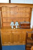 A PINE PANELLED DRESSER, with three tier plate rack, three short drawers and cupboard base,