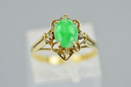 A JADE AND DIAMOND RING, the central oval jade cabochon within an open surround claw set with four