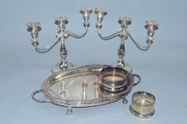 A PAIR OF SILVER PLATED THREE LIGHT CANDELABRA, together with two plated bottle coasters and an oval