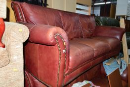 A BURGUNDY LEATHER TWO PIECE LOUNGE SUITE, comprising of two three seater sofa's