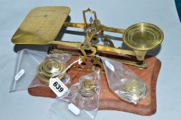 A SET OF BRASS POSTAGE SCALES, with a quantity of weights, mounted on a wooden plinth