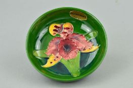 A SMALL MOORCROFT POTTERY FOOTED BOWL, 'Orchid' pattern on green ground, impressed marks to base,