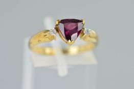 A 9CT GOLD GEM RING, designed as a central triangular cut red gem assessed as garnet, flanked by two