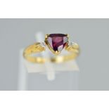 A 9CT GOLD GEM RING, designed as a central triangular cut red gem assessed as garnet, flanked by two