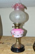 AN EARLY 20TH CENTURY OIL LAMP with a pink glass reservoir above an Art Nouveau panelled stand,