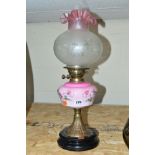 AN EARLY 20TH CENTURY OIL LAMP with a pink glass reservoir above an Art Nouveau panelled stand,