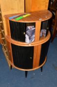 A MID 20TH CENTURY WALNUT AND EBONISED ROLL FRONT DEMI LUNE DRINKS CABINET on cylindrical leg,