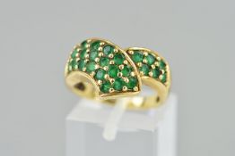 A 9CT GOLD EMERALD DRESS RING, of a curved interlinking design pave set with circular emeralds,