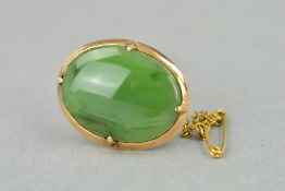 A JADE BROOCH, of oval outline to the plain surround with safety clasp, stamped 9ct, length 27mm,