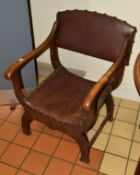 AN EARLY 20TH CENTURY CROSS FRAMED ARMCHAIR with brown leather seat and back