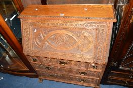 AN EARLY 20TH CENTURY CARVED OAK FALL FRONT BUREAU with fitted interior and five exterior drawers,