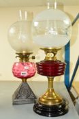 TWO OIL LAMPS WITH INTACT FROSTED GLASS SHADES AND CHIMNEYS, the first with a cranberry optic