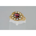 A 9CT GOLD GARNET AND PEARL CLUSTER RING, the central oval garnet within a split pearl surround (