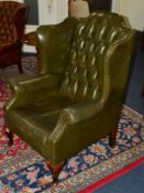 A GREEN LEATHER BUTTONED WING BACK ARMCHAIR on cabriole legs