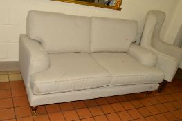 AN OATMEAL UPHOLSTERED TWO SEATER SETTEE on brass caps and casters