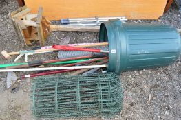 A PLASTIC BIN containing garden tools, a bird table and a roll of wire fencing