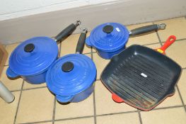 A SET OF THREE GRADUATING BLUE LE CREUSET COVERED SAUCEPANS, together with a Le Creuset red