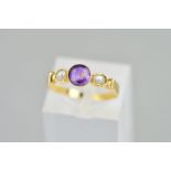 AN EARLY 20TH CENTURY AMETHYST AND PEARL RING, the central circular amethyst flanked by a split