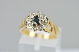 A 9CT GOLD SAPPHIRE AND DIAMOND CLUSTER RING, the central circular sapphire within a single cut