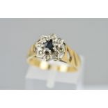 A 9CT GOLD SAPPHIRE AND DIAMOND CLUSTER RING, the central circular sapphire within a single cut