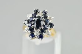 A 9CT GOLD SAPPHIRE AND DIAMOND CLUSTER DRESS RING, designed as a central oval sapphire within a