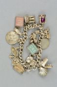 A CHARM BRACELET, the curb link bracelet suspending sixteen charms to include a hinged typewriter