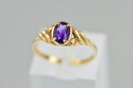 A 9CT GOLD AMETHYST RING, with a central oval amethyst and decorative shoulders, hallmarked