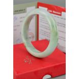 A MODERN JADE (JADITE) SOLID SLAVE BANGLE, pale green in colour measuring approximately 60.0mm inner