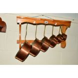 A SET OF SIX COPPER GRADUATING PANS with a pine hanging rack