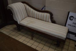 A VICTORIAN FLAME MAHOGANY CHAISE LONGUE, with a scrolled end and baluster legs on brass casters