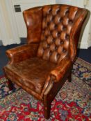 A BROWN LEATHER BUTTONED WING BACK ARMCHAIR