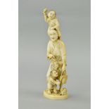 A LATE 19TH CENTURY JAPANESE IVORY OKIMONO, carved with a young boy holding a stick standing on a