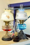 THREE GLASS RESERVOIR OIL LAMPS, two with shades and chimneys, a blue glass example on a cast iron