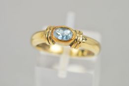 A 9CT GOLD AQUAMARINE RING, the oval aquamarine within a collet setting flanked by banded detail, to