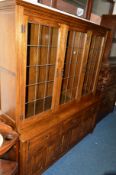 A REPRODUCTION OAK LEAD GLAZED THREE DOOR BOOKCASE above three drawers, approximate width 168cm x