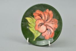 A MOORCROFT POTTERY PIN DISH, 'Hibiscus' pattern on green ground, impressed marks and paper label to