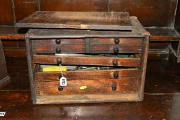A DISTRESSED OAK ENGINEERS CHEST with seven various drawers containing various tools including