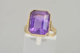 A 9CT GOLD AMETHYST RING, the rectangular amethyst collet set to the tapered shoulders and plain