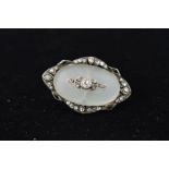 AN EARLY 20TH CENTURY DIAMOND AND QUARTZ OVAL BROOCH centering on an oval cabochon cut frosted