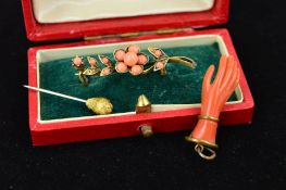 THREE ITEMS OF JEWELLERY to include a carved hand pendant, a flower brooch set with circular coral